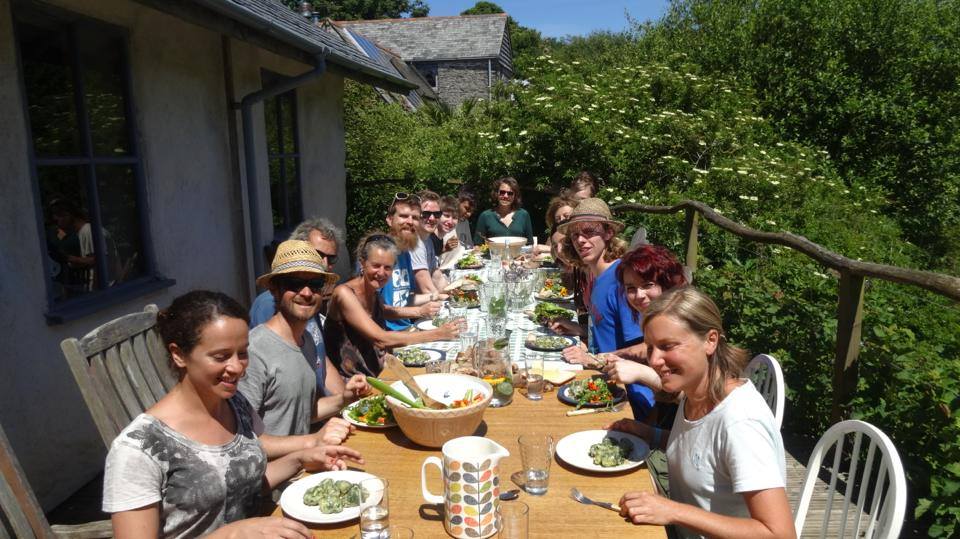 Early summer feast at Cotna Eco Retreat on strawbale barn deck with wwoof volunteers from Italy, Spain, France, Chile and South Africa and Cornwall, eating home-made gnocchi and basil pesto with organic salad leaves and foraged elderflower cordial
